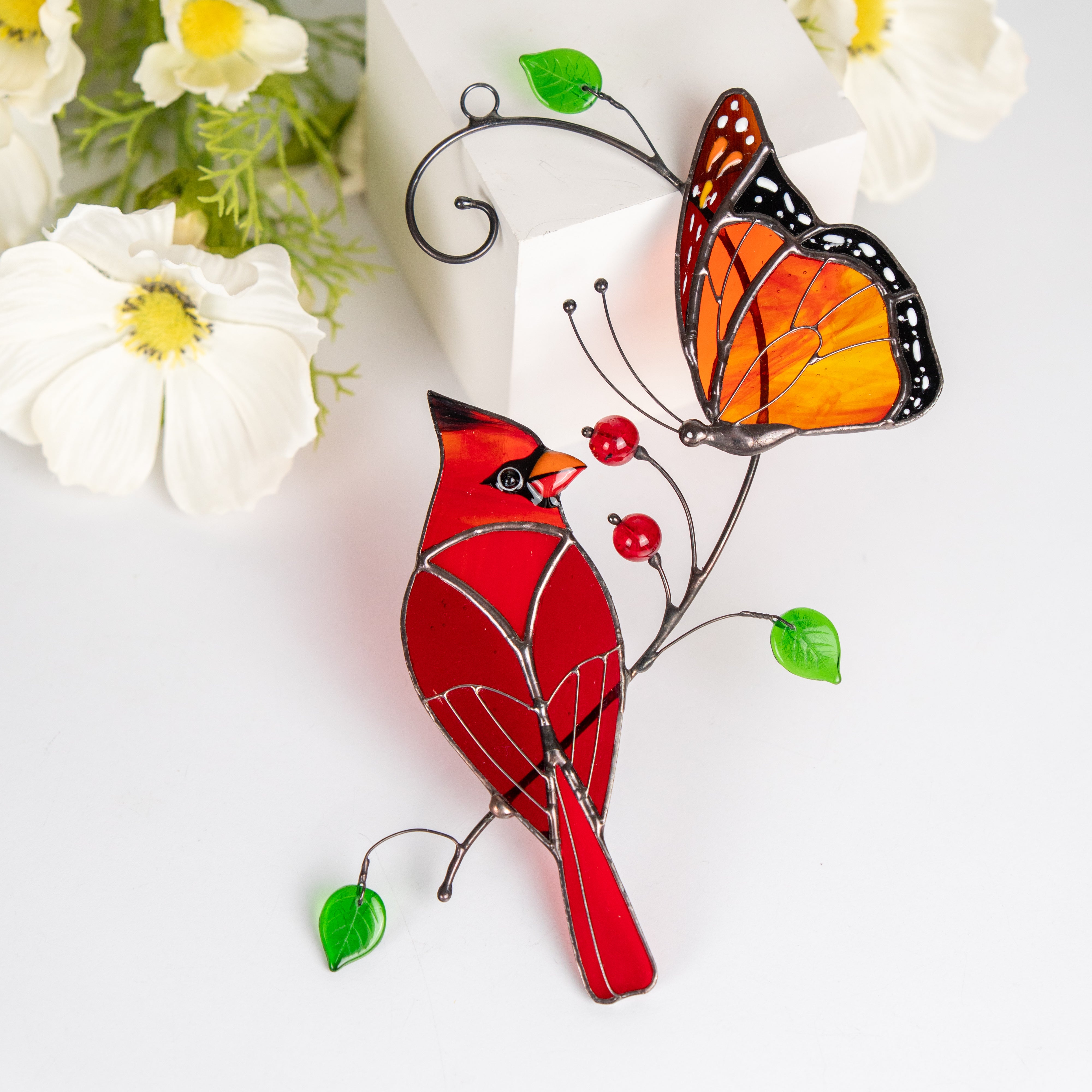 Close-up of a stained glass cardinal and monarch butterfly suncatcher.