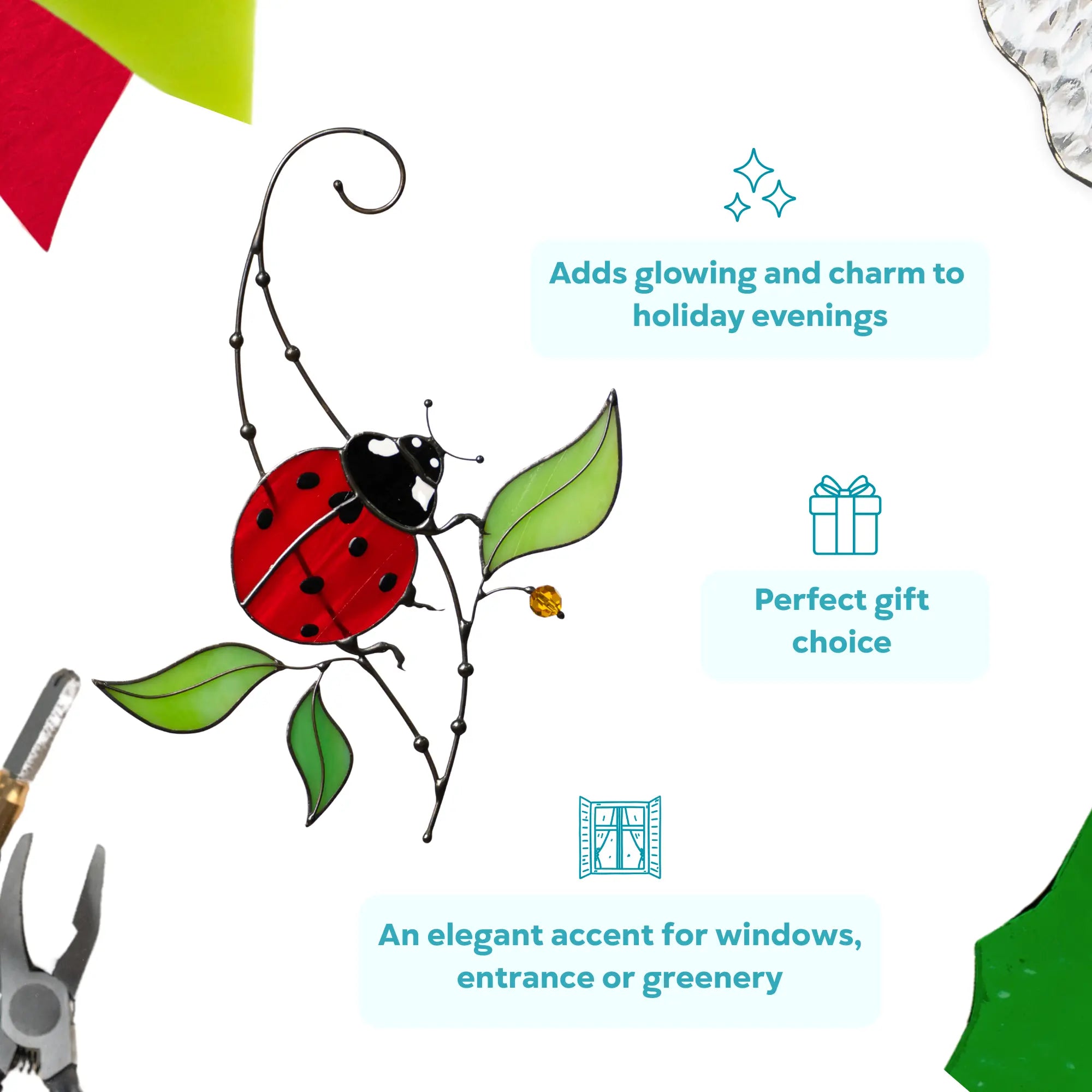 Ladybug stained glass ornament with red wings and green leaves hanging on a thin silver branch with a suction cup for easy window display.