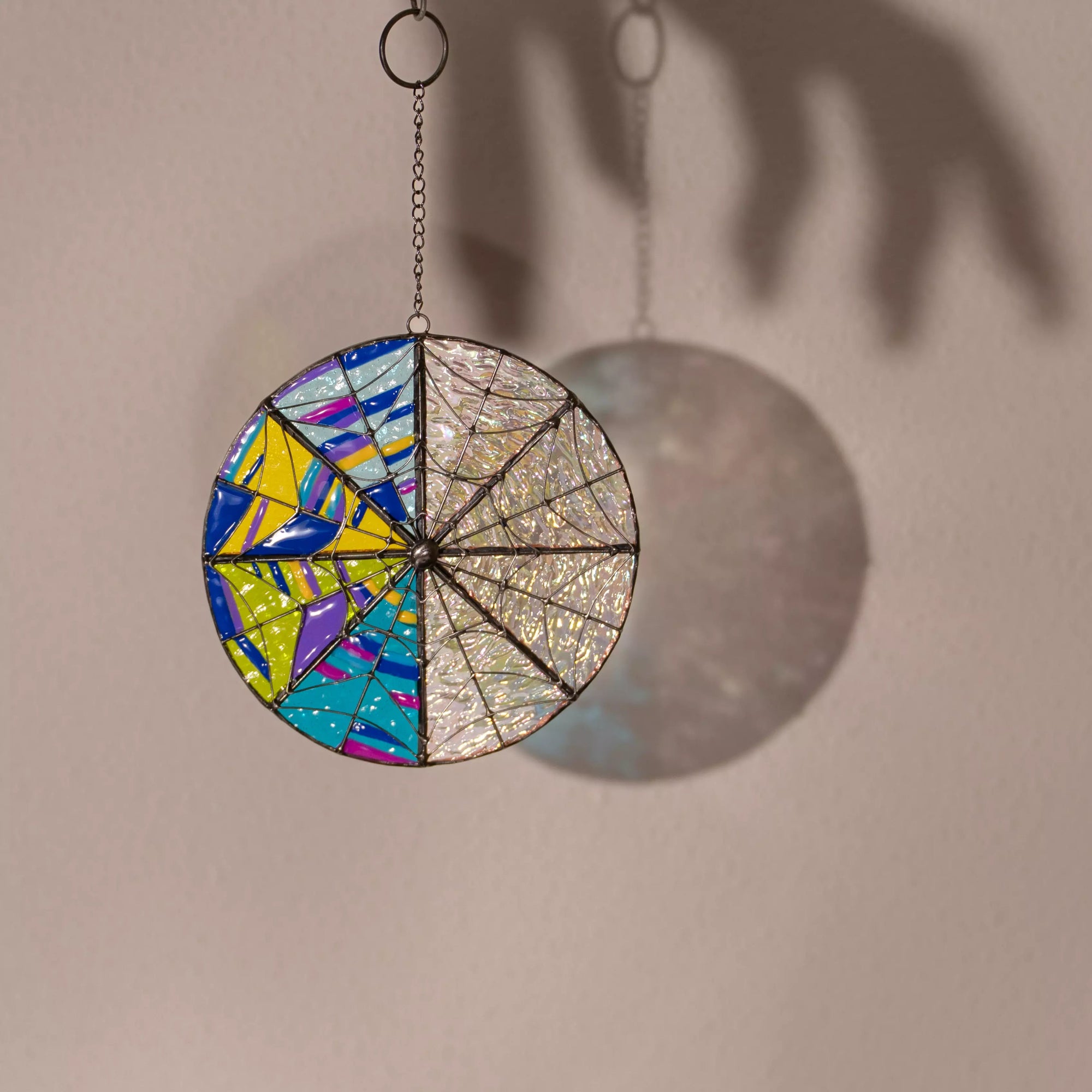 Stained glass round suncatcher casting soft rainbow shadow on the wall