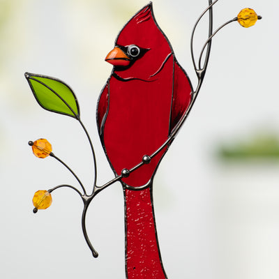Detailed view of stained glass cardinal bird with orange beak and decorative botanical elements.