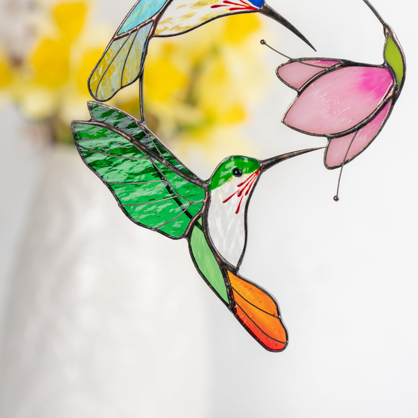 Close-up view of the vivid green  hummingbird and pink flower made from stained glass