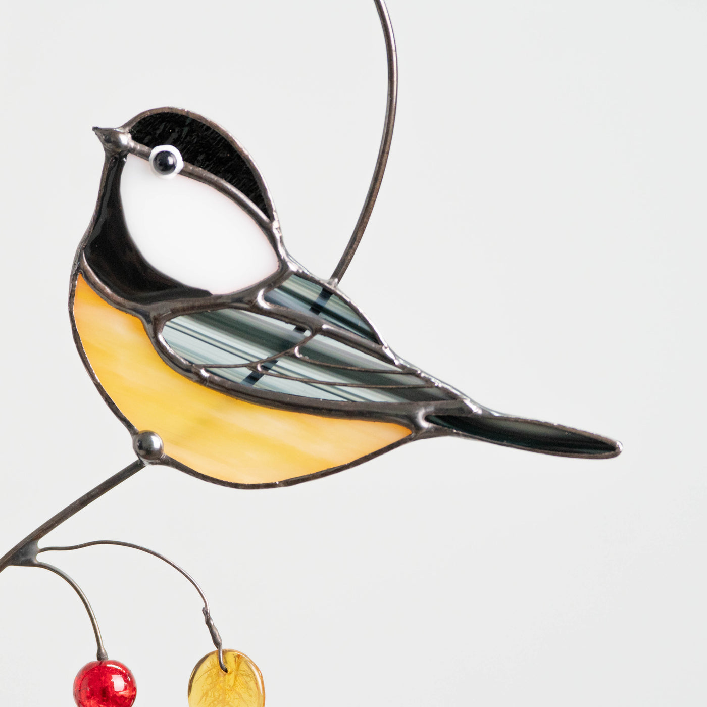 Detailed view of a stained glass chickadee showing striped glass wings and yellow belly with bead decorations.