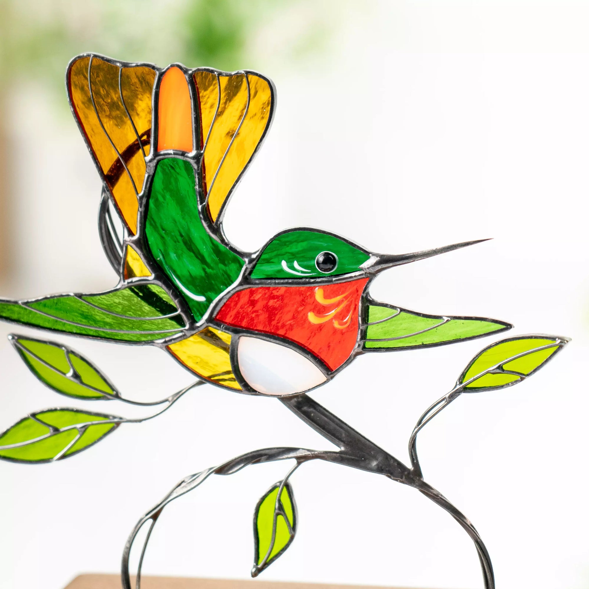 Detailed view of stained glass hummingbird’s torso and leaves, highlighting textures and bright color transitions.