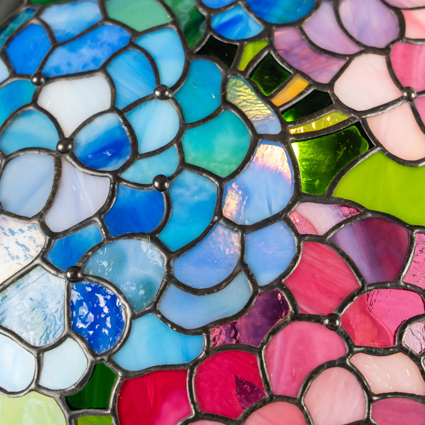 Vivid stained glass mosaic in blue and pink flower petals with rich texture and shine.