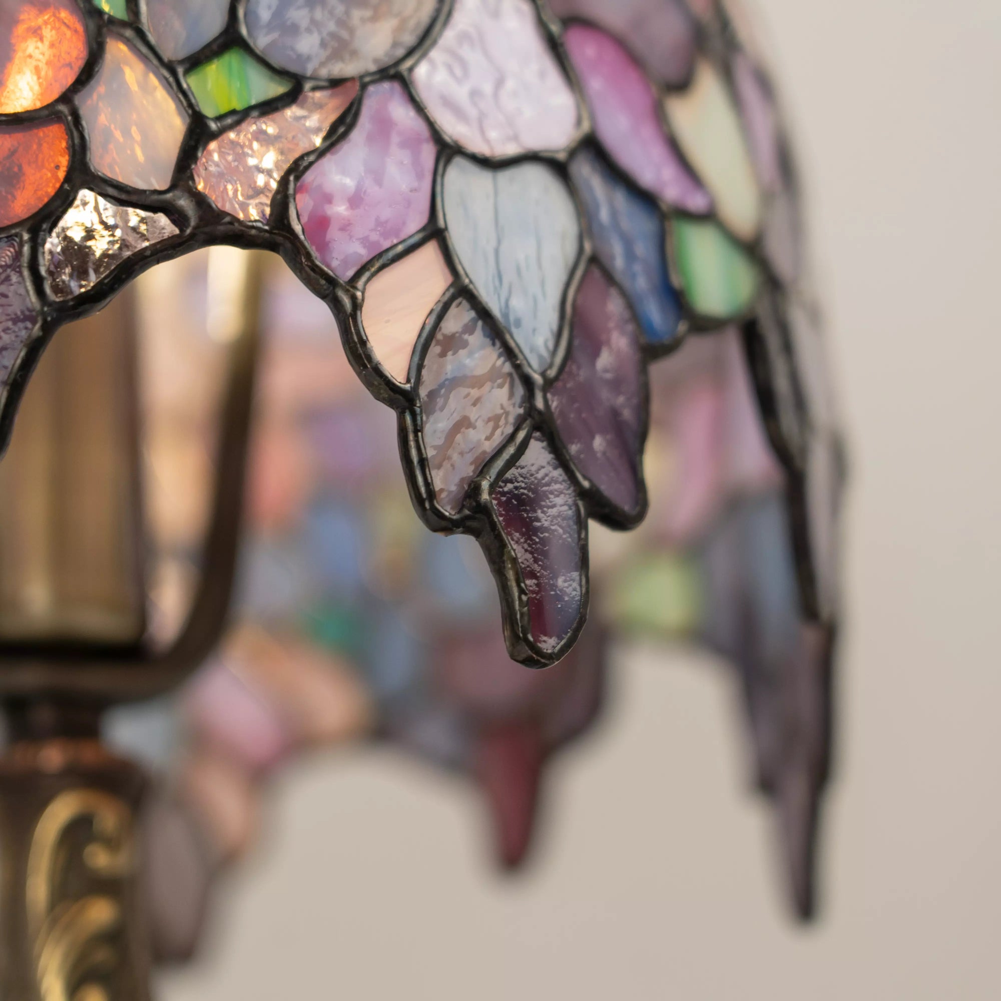 Close-up view of a colorful stained glass Wisteria lamp with a blurred background