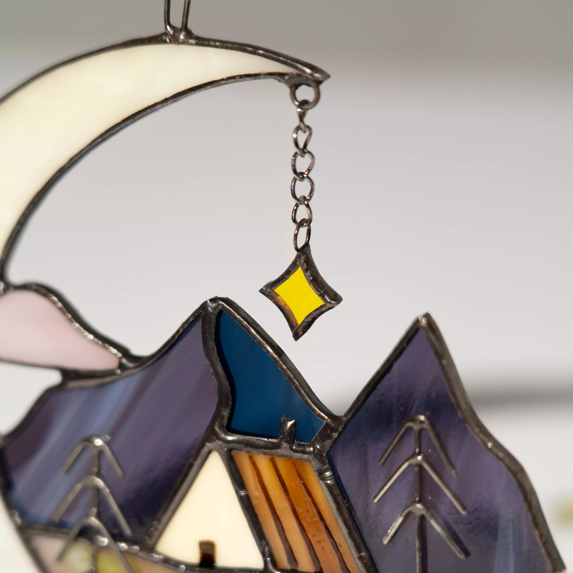 Close-up view of stained glass crescent moon suncatcher with celestial details