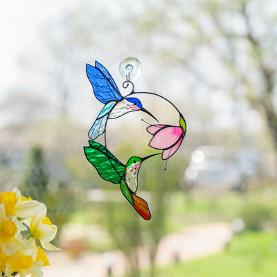 Suncatcher with green and blue hummingbirds on window.
