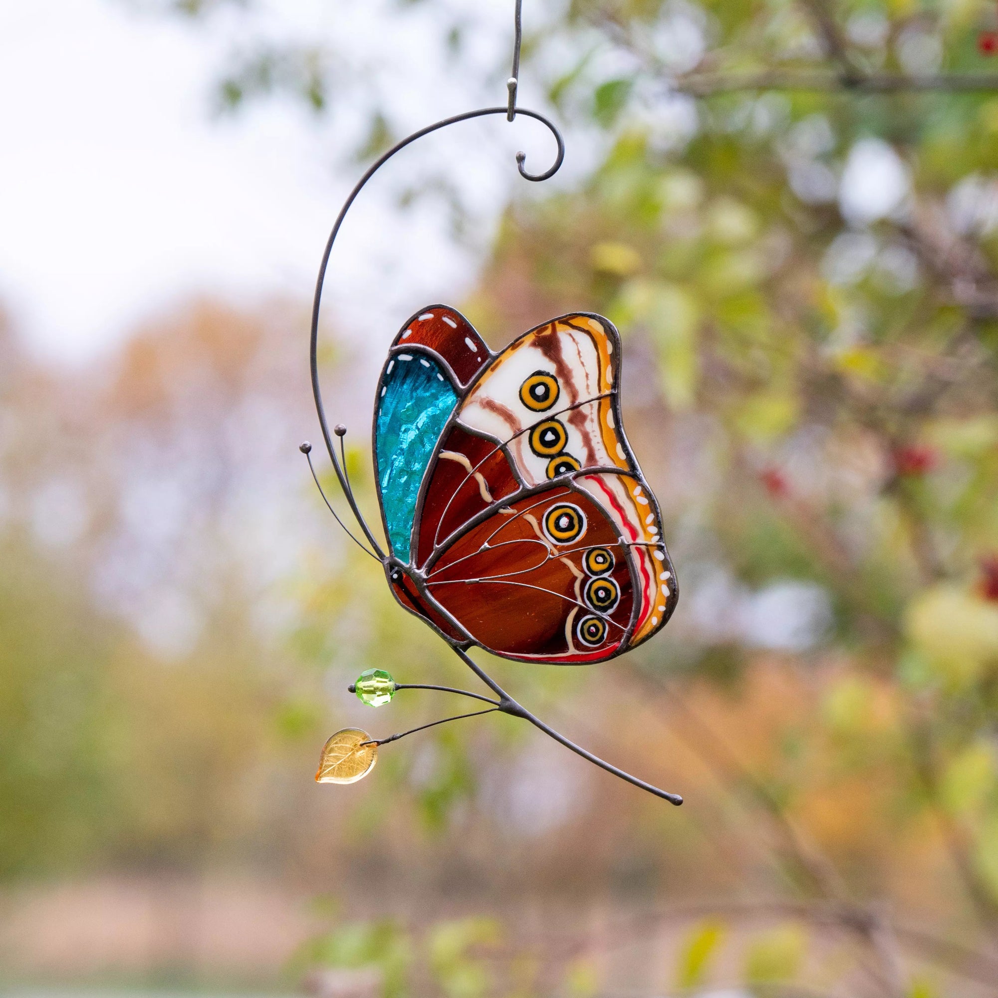 Vibrant stained glass butterfly with detailed wings hanging on tree branch