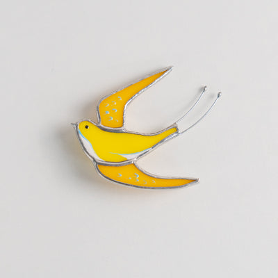 Stained glass brooch of a yellow swallow bird