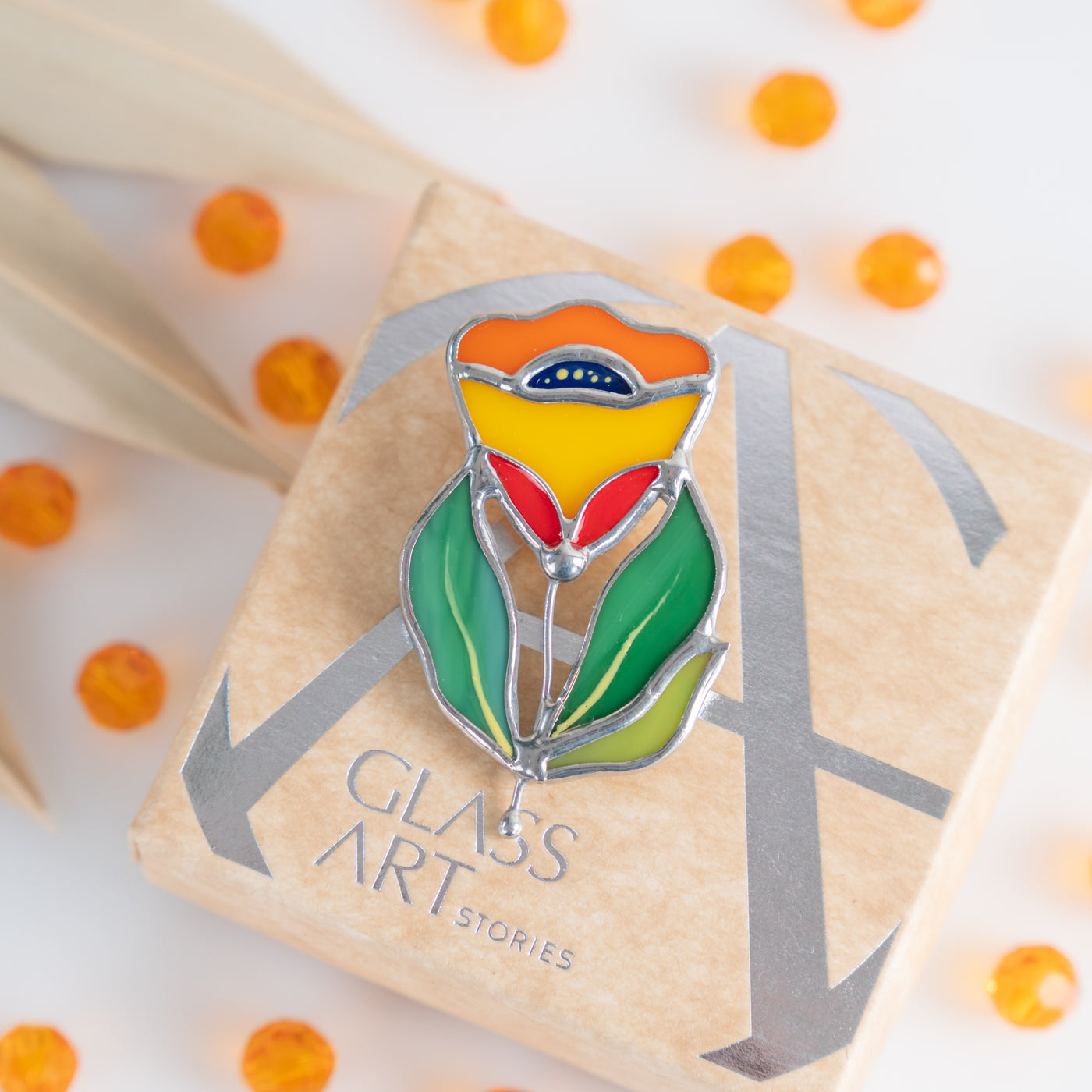 Stained glass zinnia flower brooch on a brand box