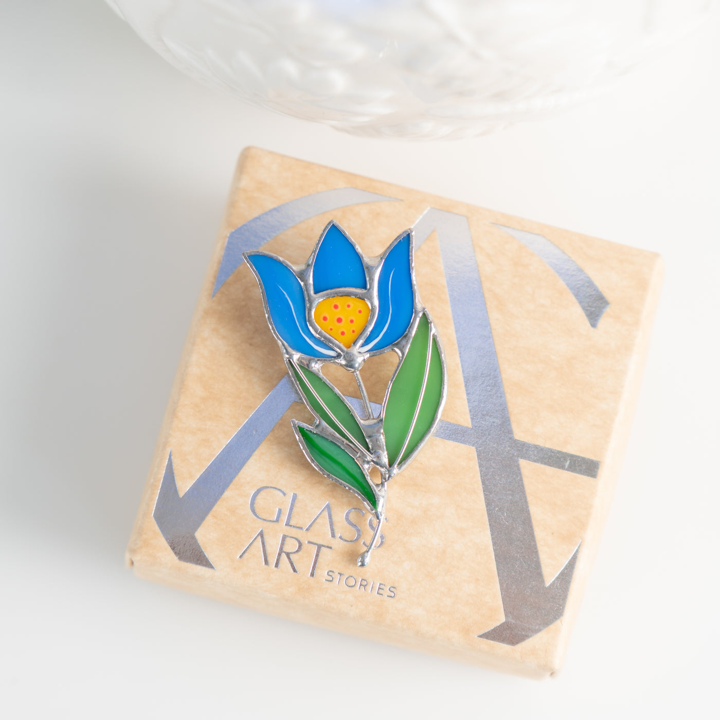 Stained glass blue anemone flower pin on a brand box