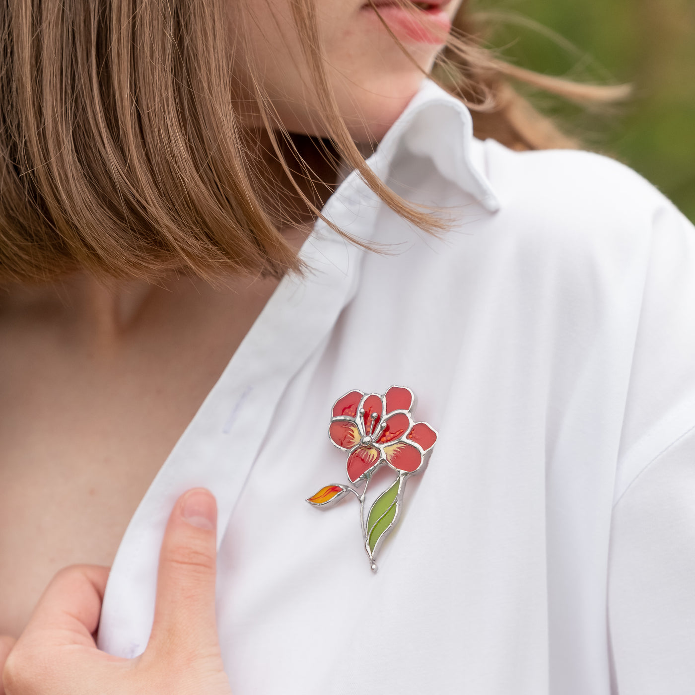 Red aster stained glass brooch on a white shirt