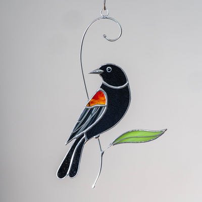 red winged blackbird stained glass light catcher sitting on the branch 