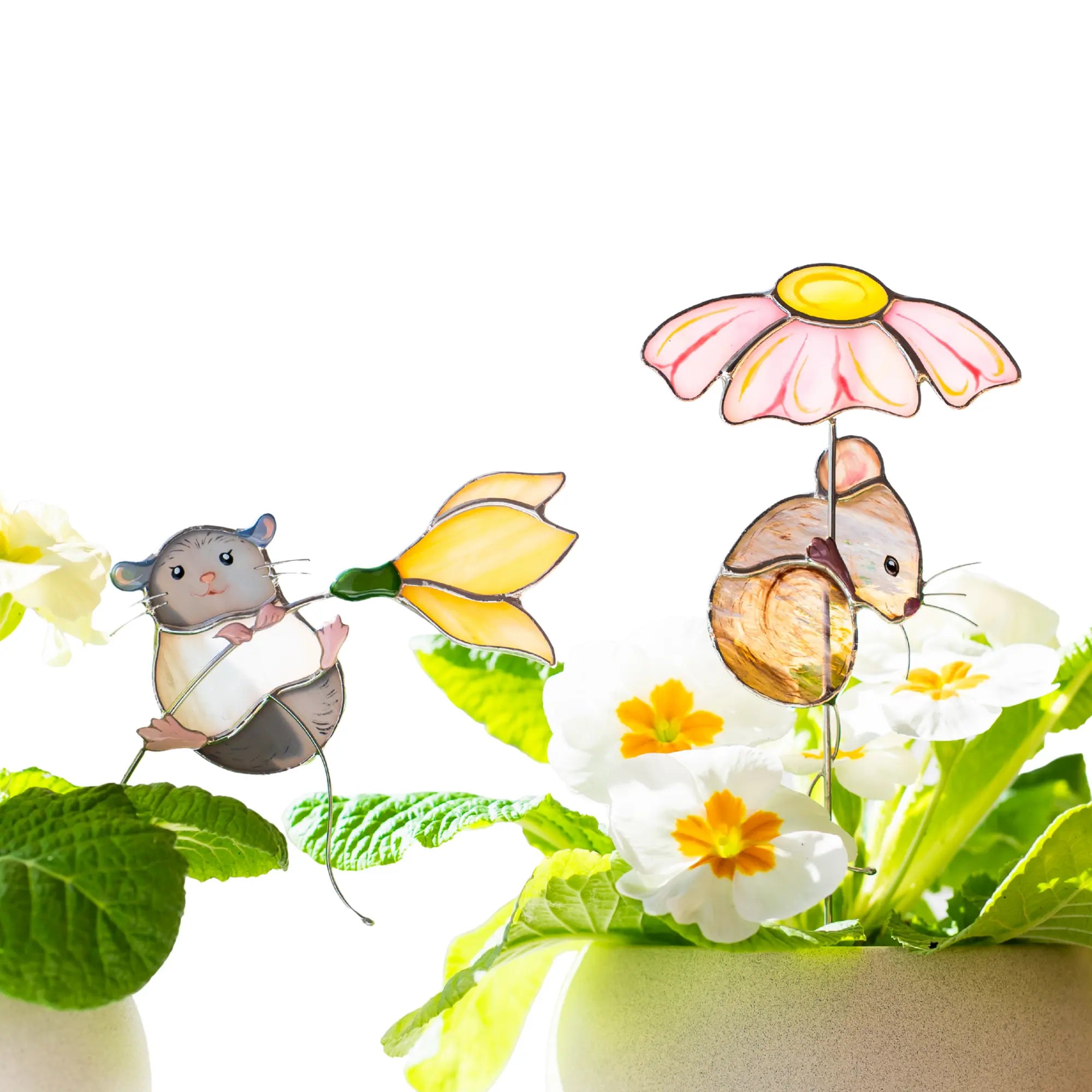 Stained glass plant stakes with mice holding flowers and surrounded by plants and flowers on a white background.