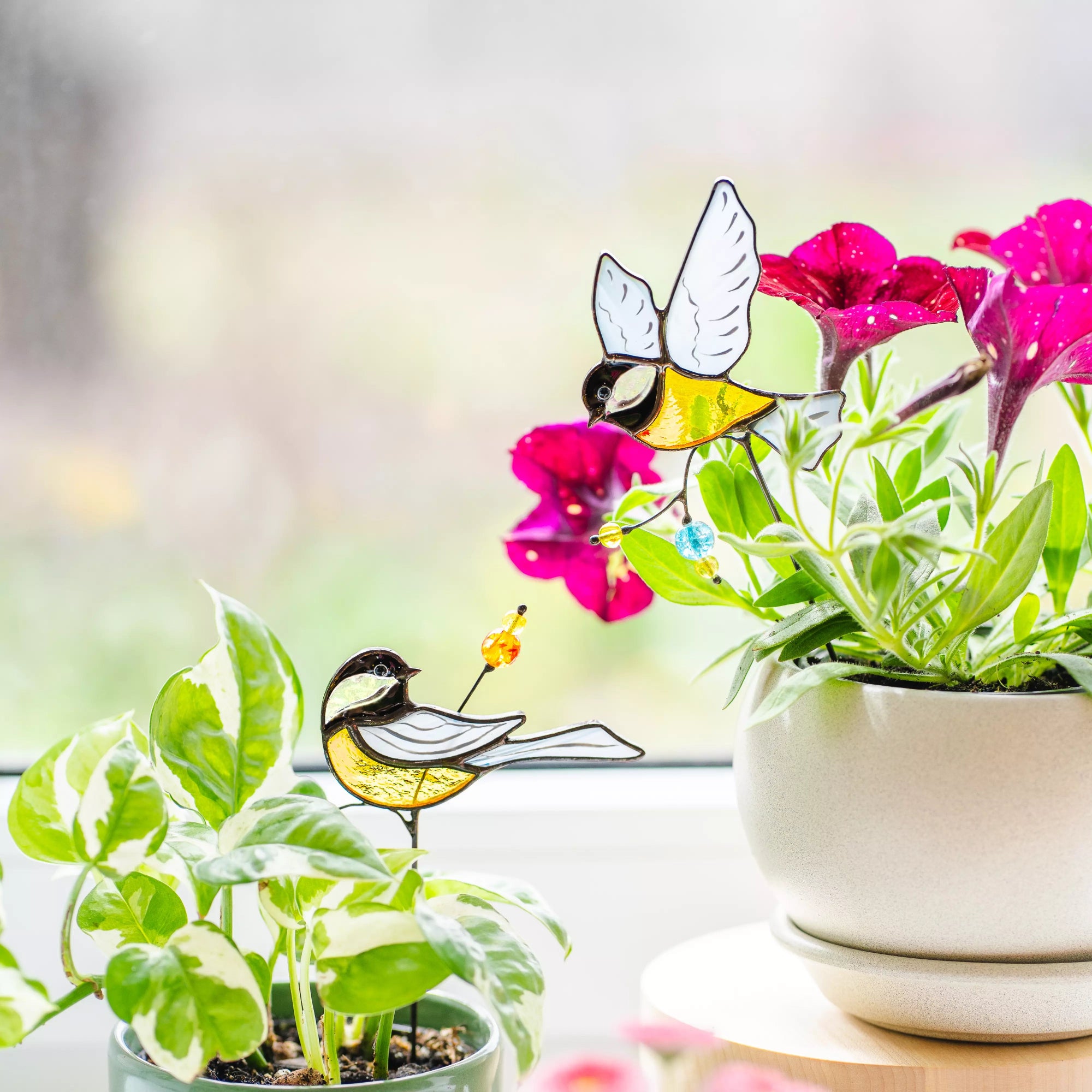 Stained glass birds with pink flowers and plants on a blurred background