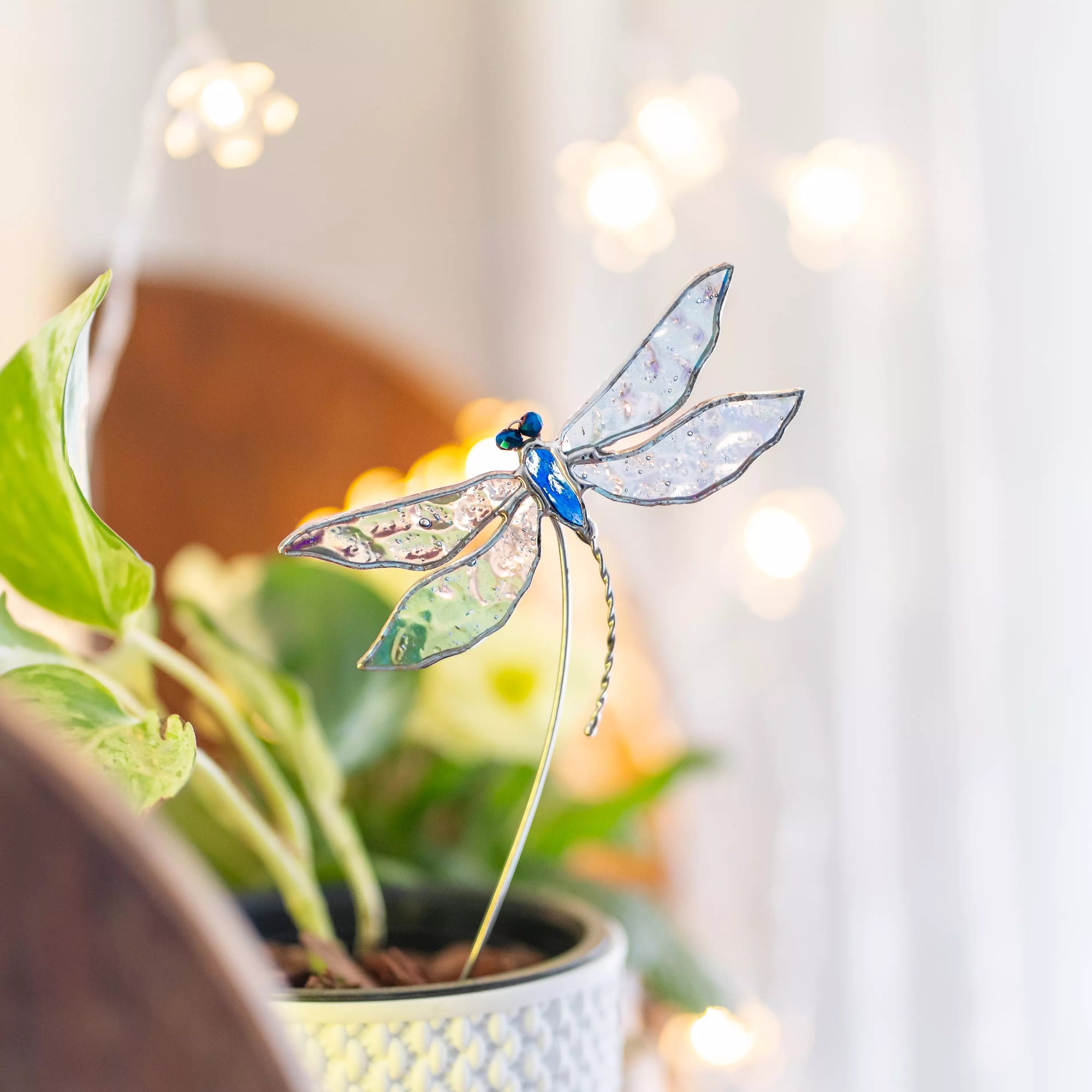 Stained glass dragonfly on a plant with a blurred background