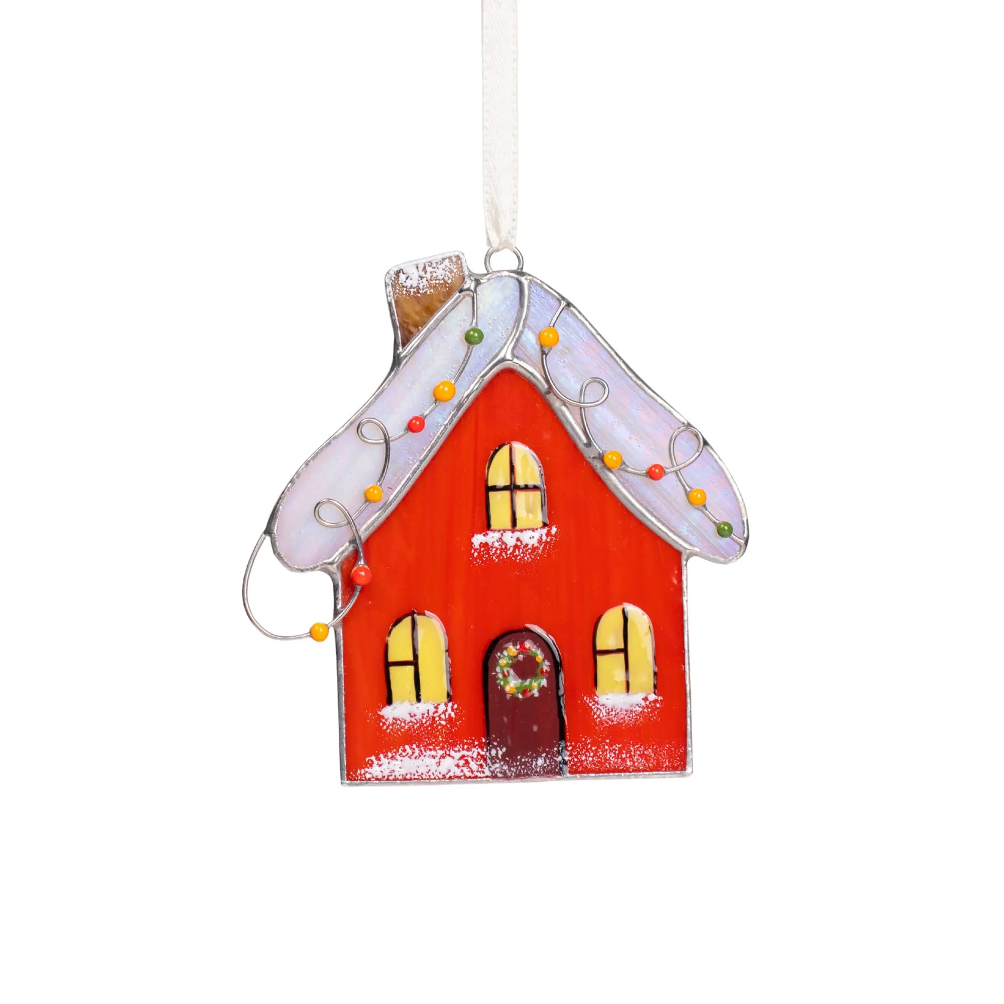 Stained glass gingerbread house ornament with a red body, white roof, and yellow windows on a white background.