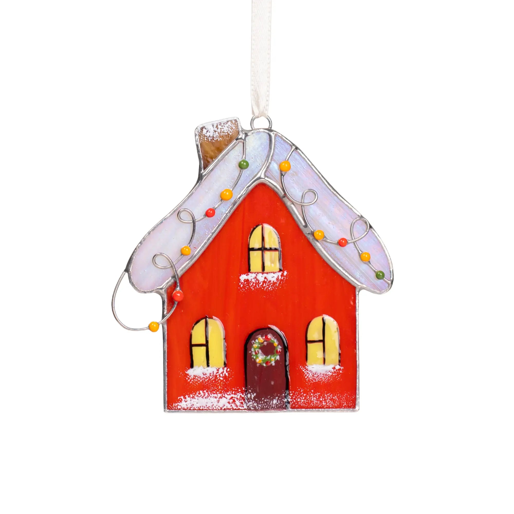 Stained glass gingerbread house ornament with a red body, white roof, and yellow windows on a white background.