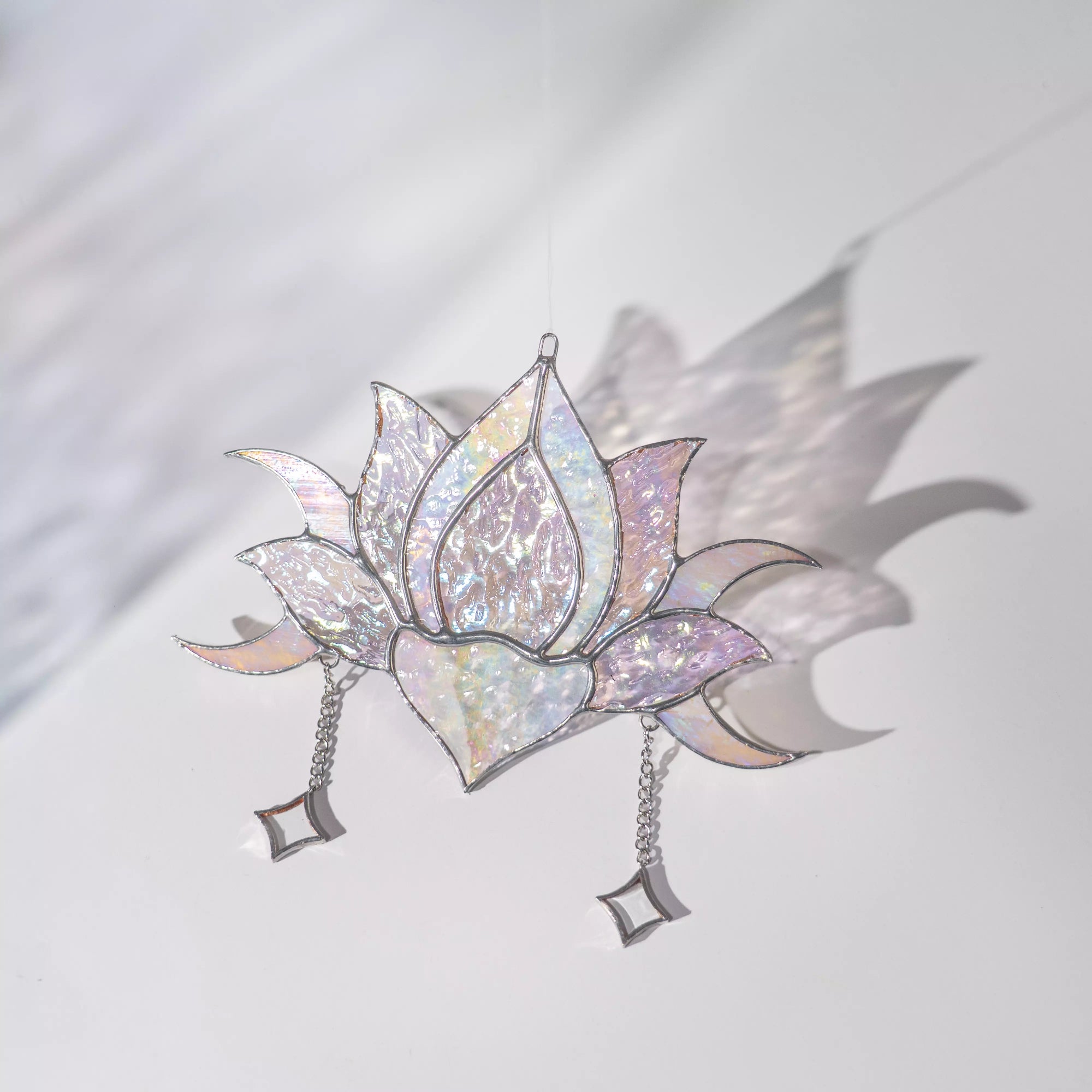 Stained glass lotus flower with iridescent finish and chain on a light background