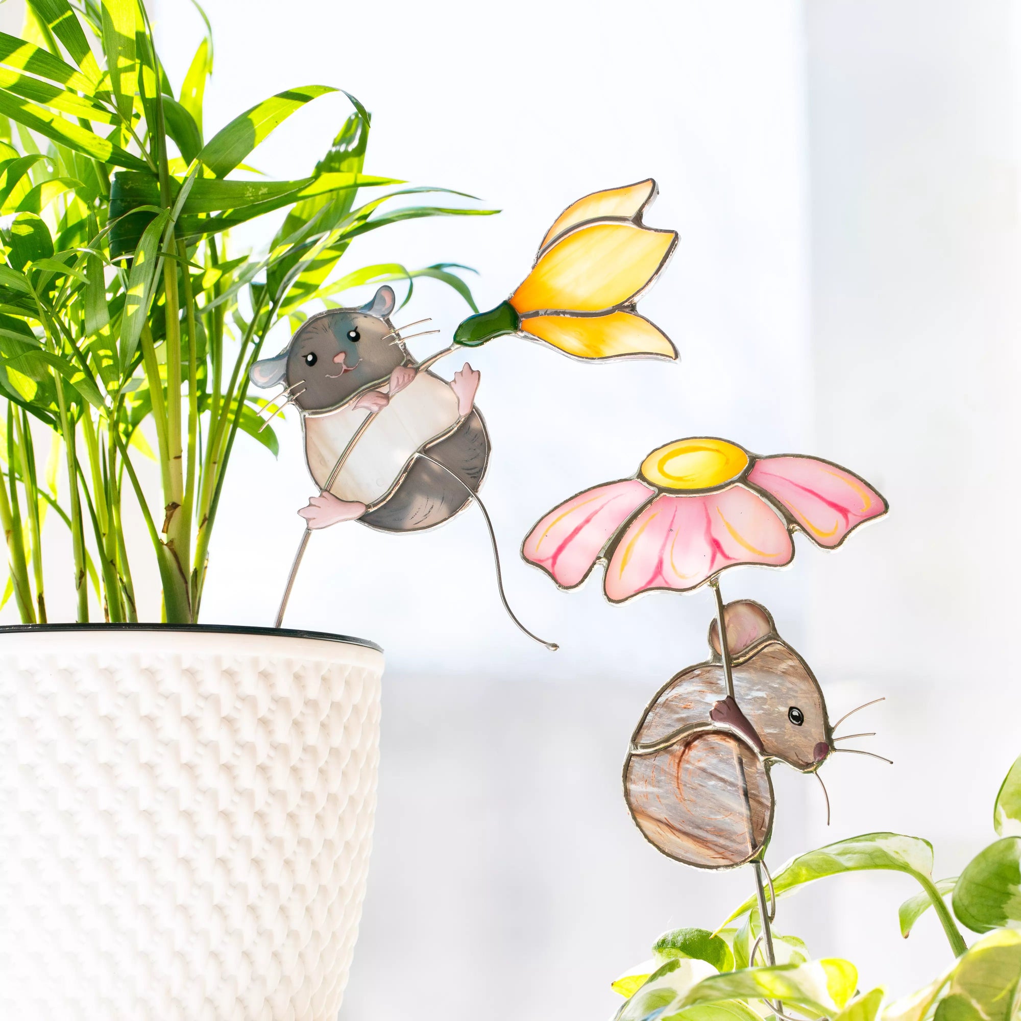 Stained glass mice plant stakes with flowers on a white background