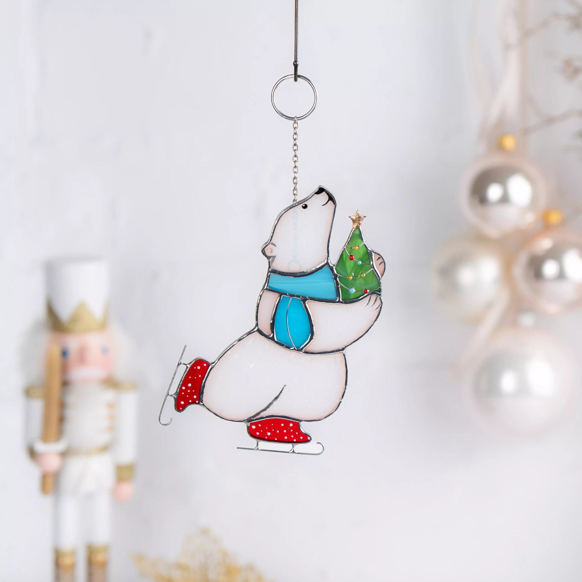 Stained glass polar bear ornament with a Christmas tree, hanging against a white background.