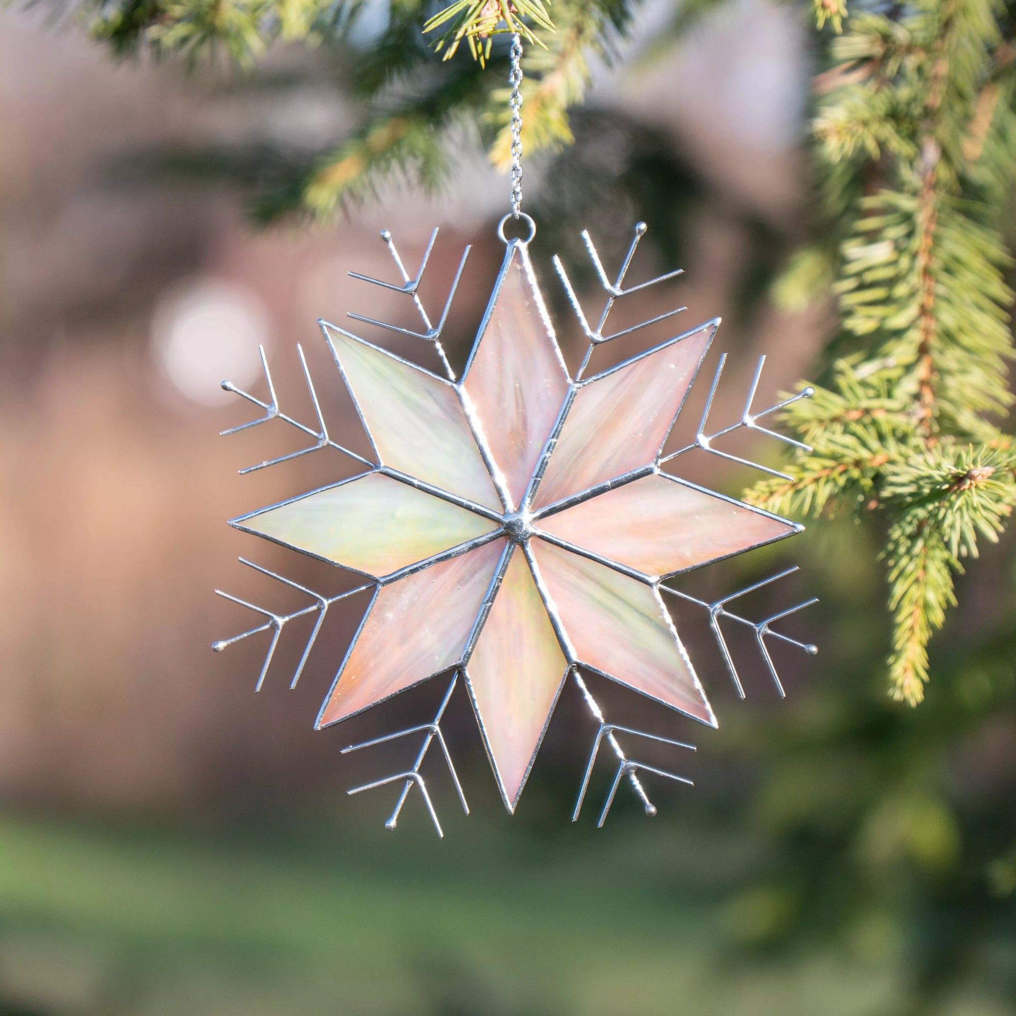 Decorative stained glass snowflake Christmas decoration hanging on a tree branch