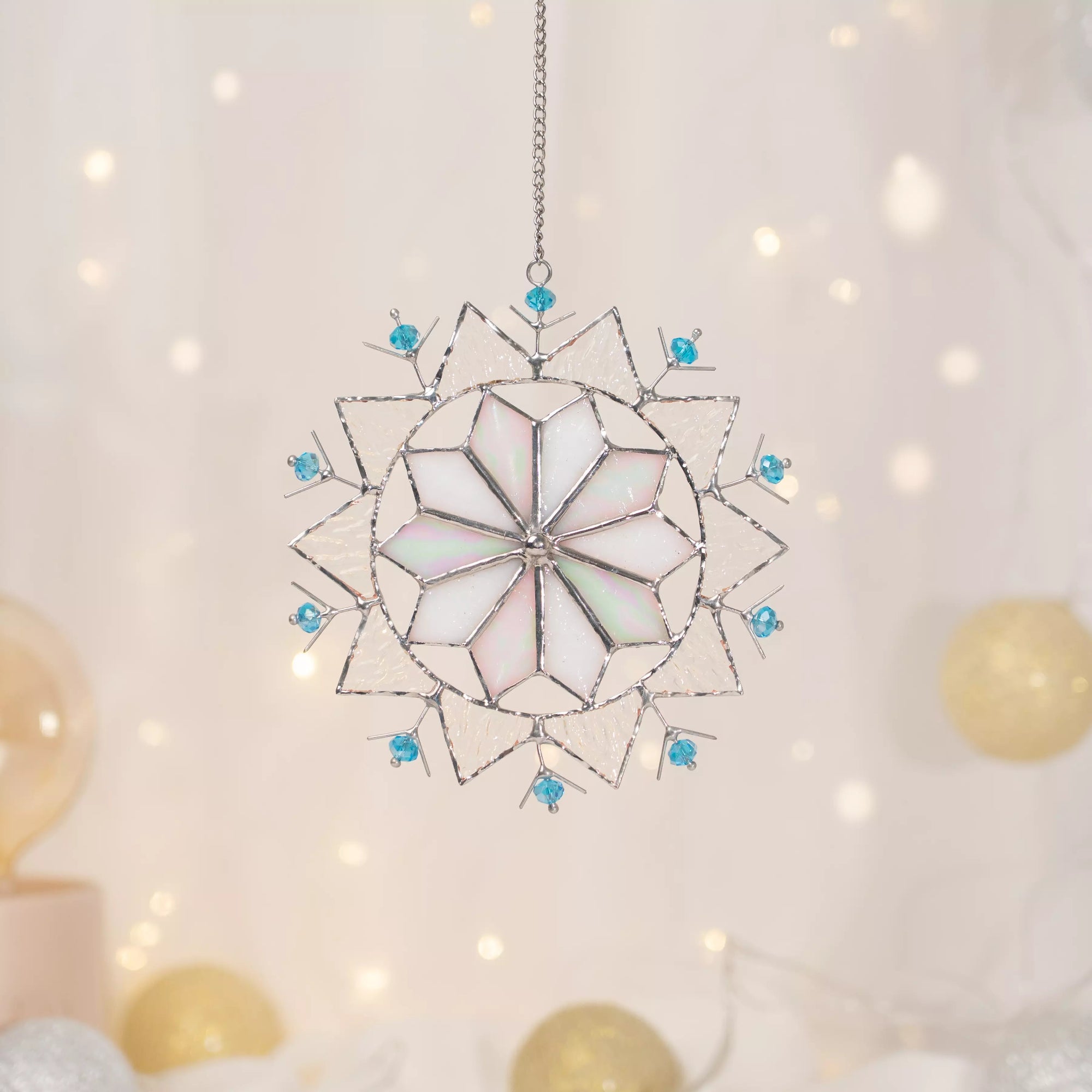 Stained glass snowflake suncacther with blue beads on a soft white background