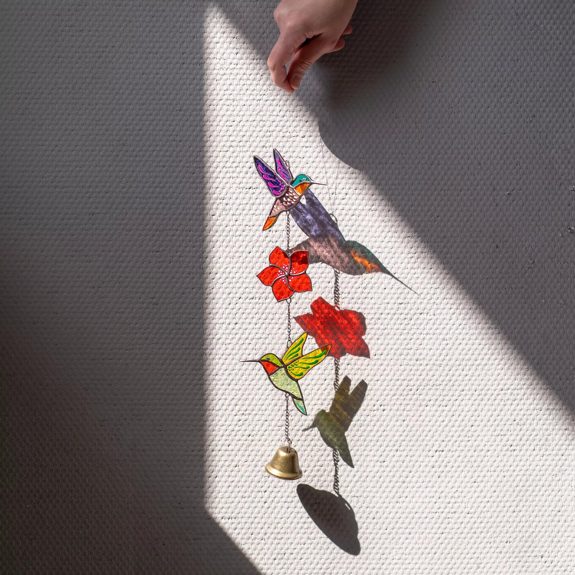 Stained glass wall hanging with colorful birds and flowers on a textured surface