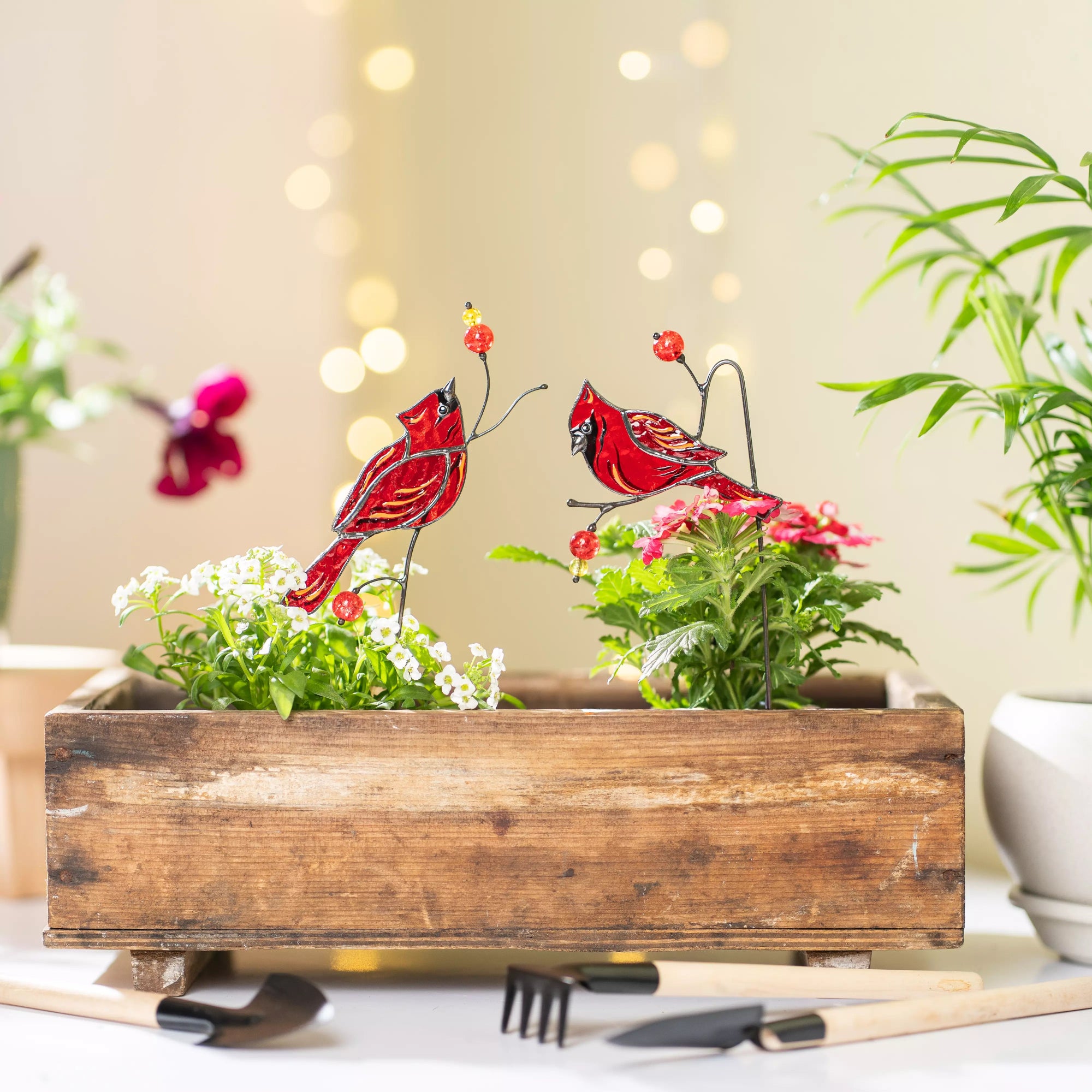 Decorative wooden planter with red cardinal birds and flowers on a blurred background