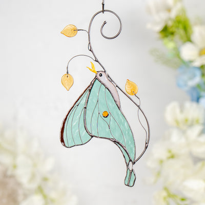 Light green stained glass luna moth with a bright amber bead and elegant curved tail.