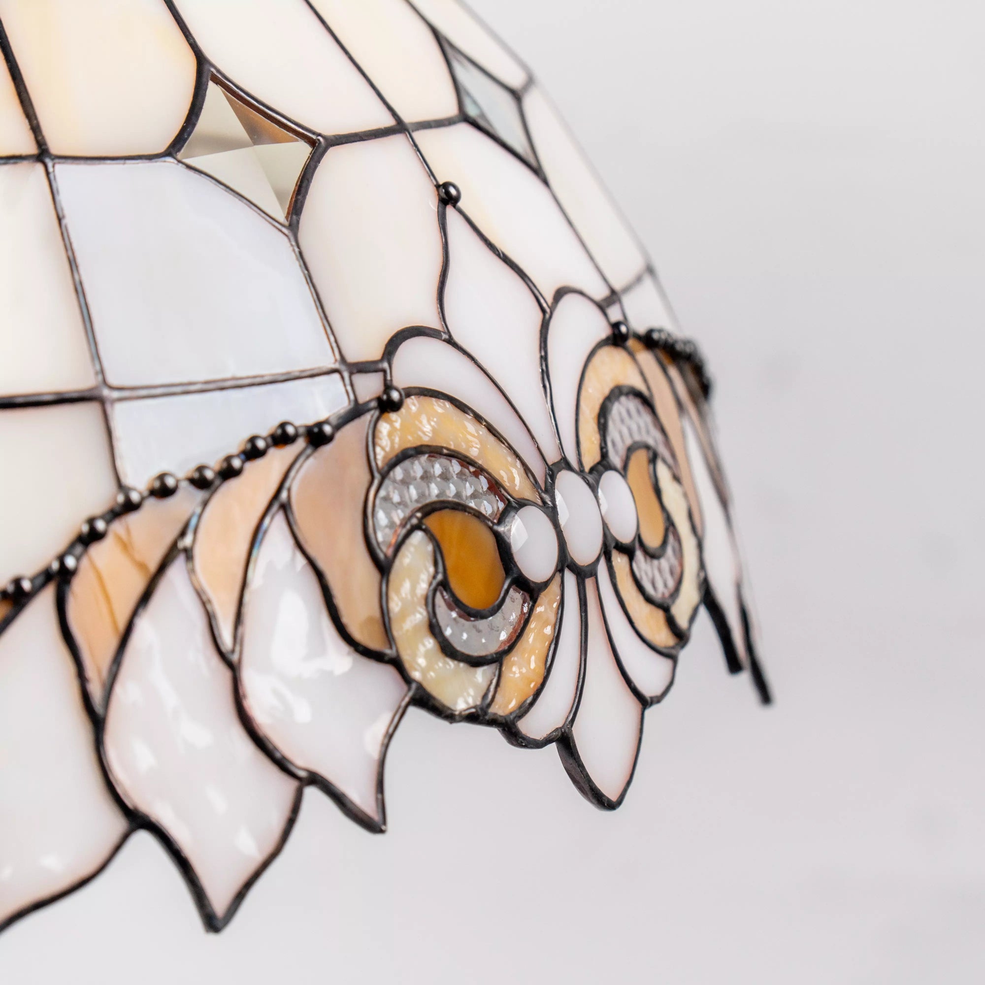Close-up of decorative bow in amber, ivory, and clear stained glass with fine soldering