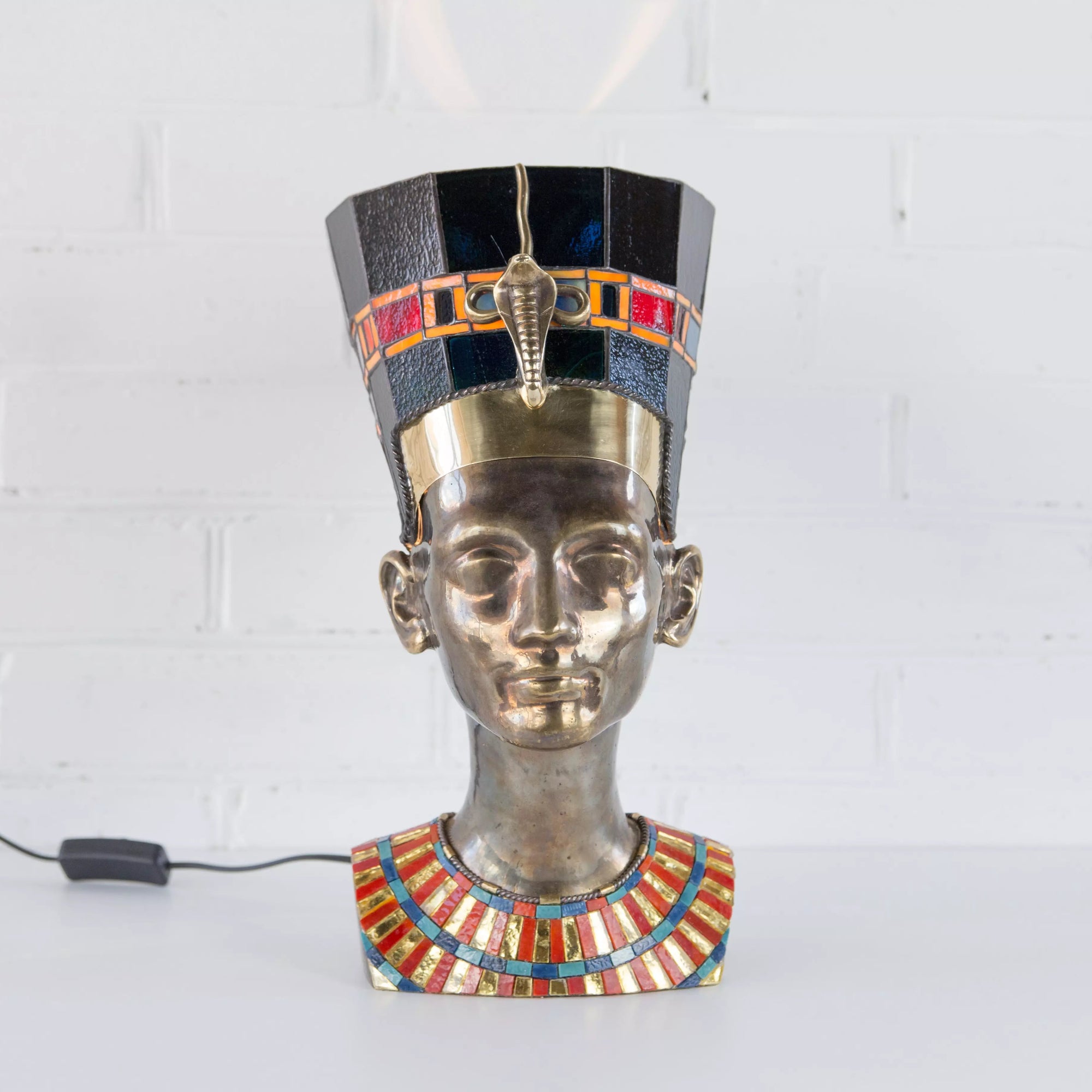 Close-up of stained glass Nefertiti design with crown, profile silhouette and glowing amber mosaic glass
