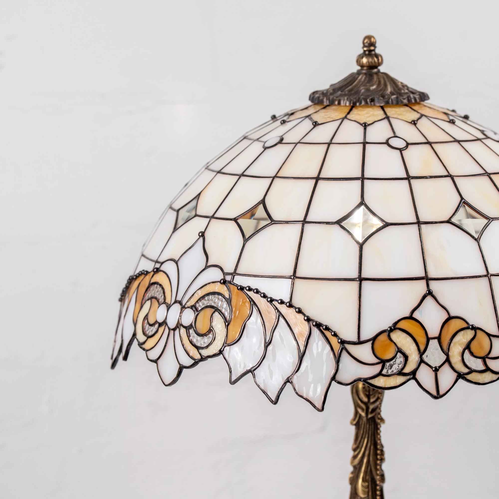 Stained glass lamp shade with floral edge detail in amber, cream, and ivory tones