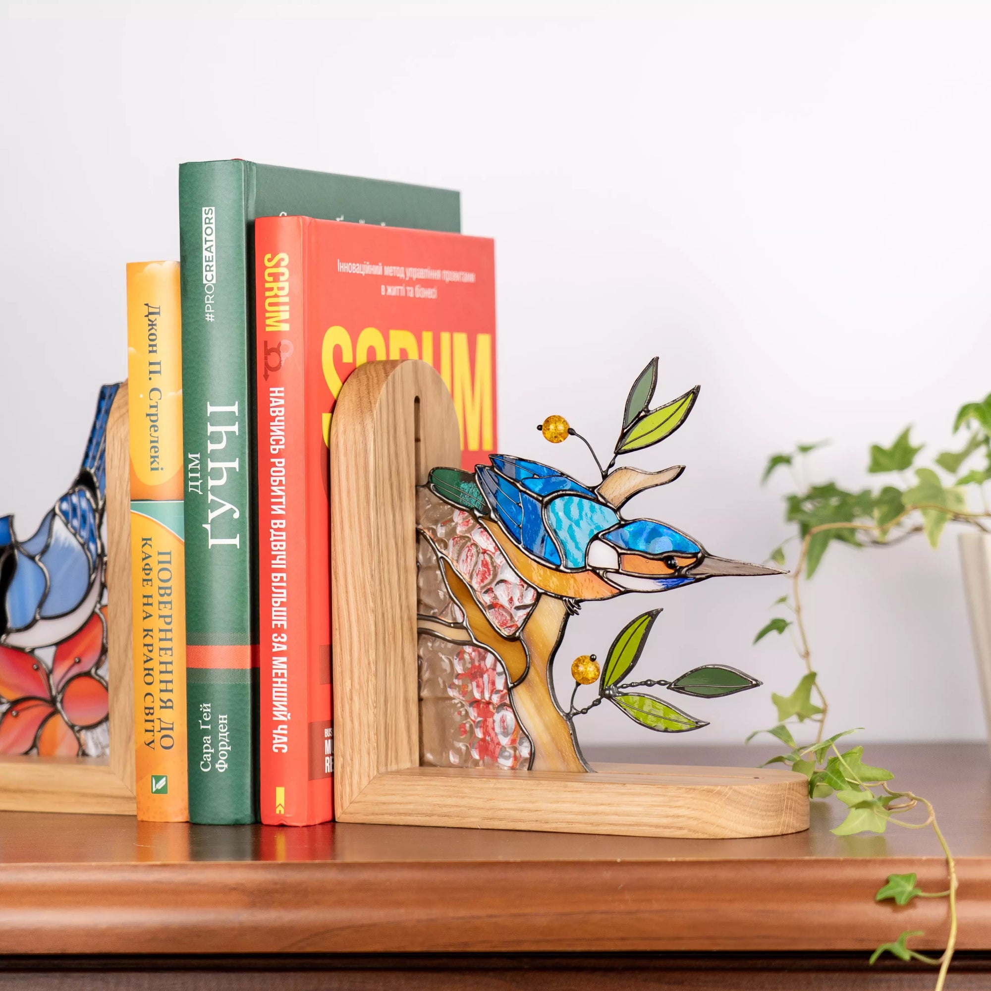 Handcrafted functional stained glass kingfisher bookend supporting books. The textured transparent glass resembles water, while the vibrant bird adds a pop of color to any display
