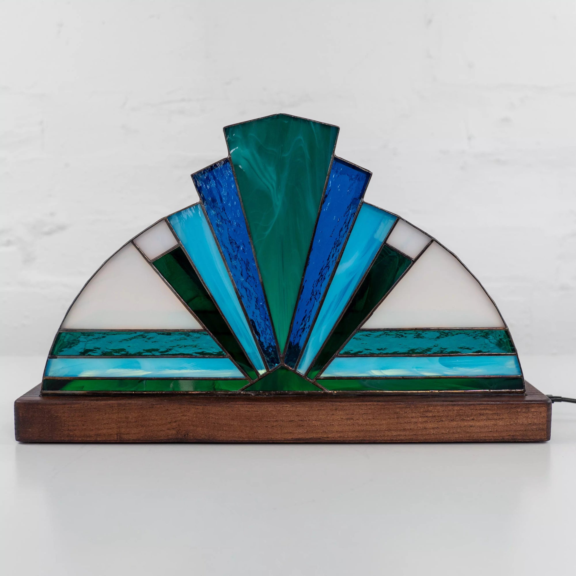 Geometric blue stained glass lamp glowing in dim light, handmade accent for cozy interiors and modern home decor.