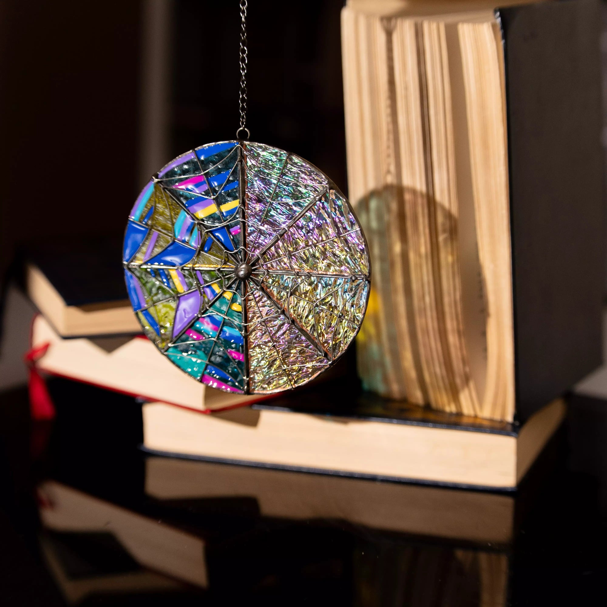 Colorful round stained glass suncatcher hanging by books for home decor