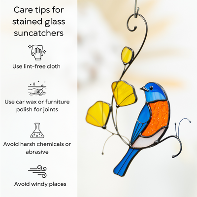 Close-up of a stained glass bluebird suncatcher with illustrated care instructions on the right