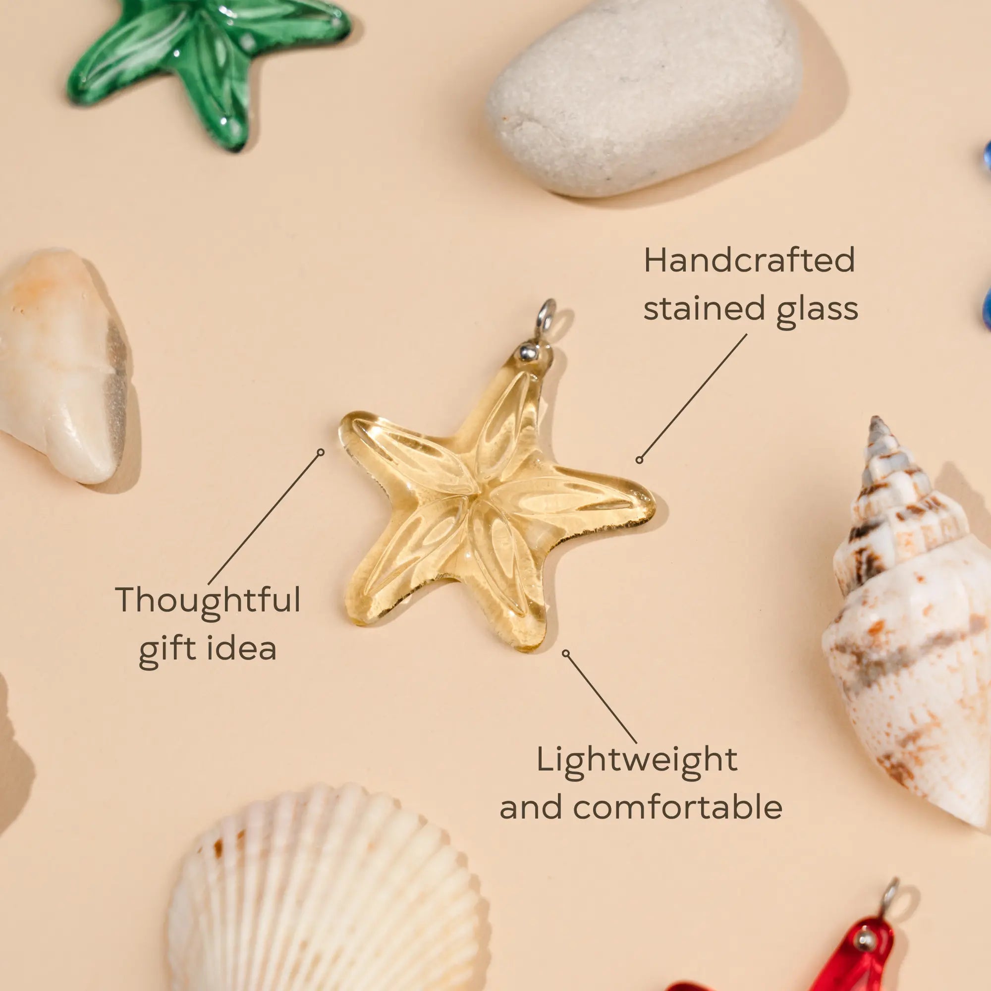 Golden stained glass starfish pendant surrounded by shells and pebbles 
as a thoughtful gift idea, handcrafted stained glass, lightweight and comfortable.