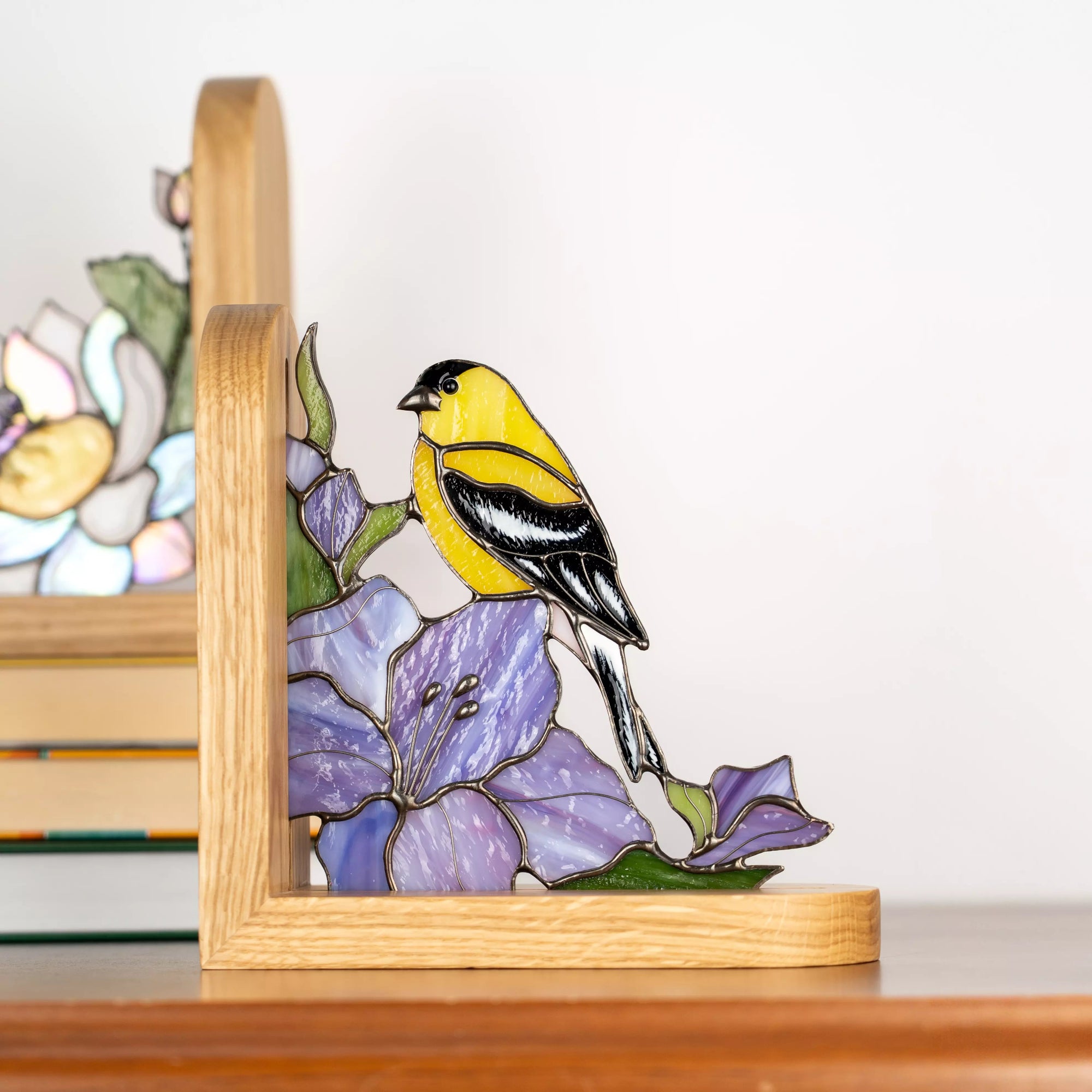 Pair of stained glass bookends featuring a goldfinch bird and floral design, handmade glass decor combining functional book support with colorful nature-inspired accents for shelves and interiors