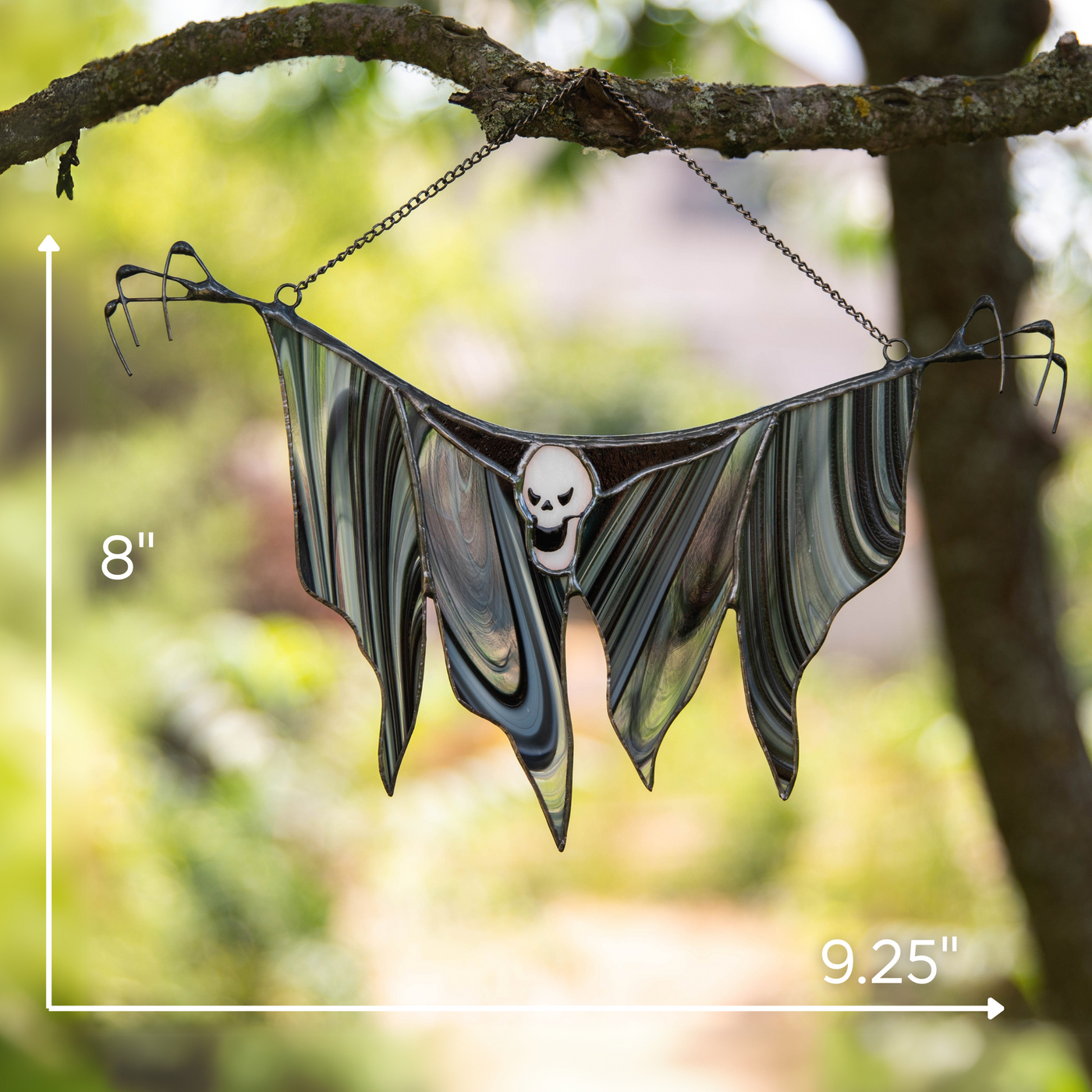 Glass Grim Reaper hanging on a tree branch with measurement overlay showing 8 x 9.25 inches