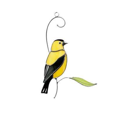 Yellow and black stained glass goldfinch perched with a green glass leaf, perfect for window decor.