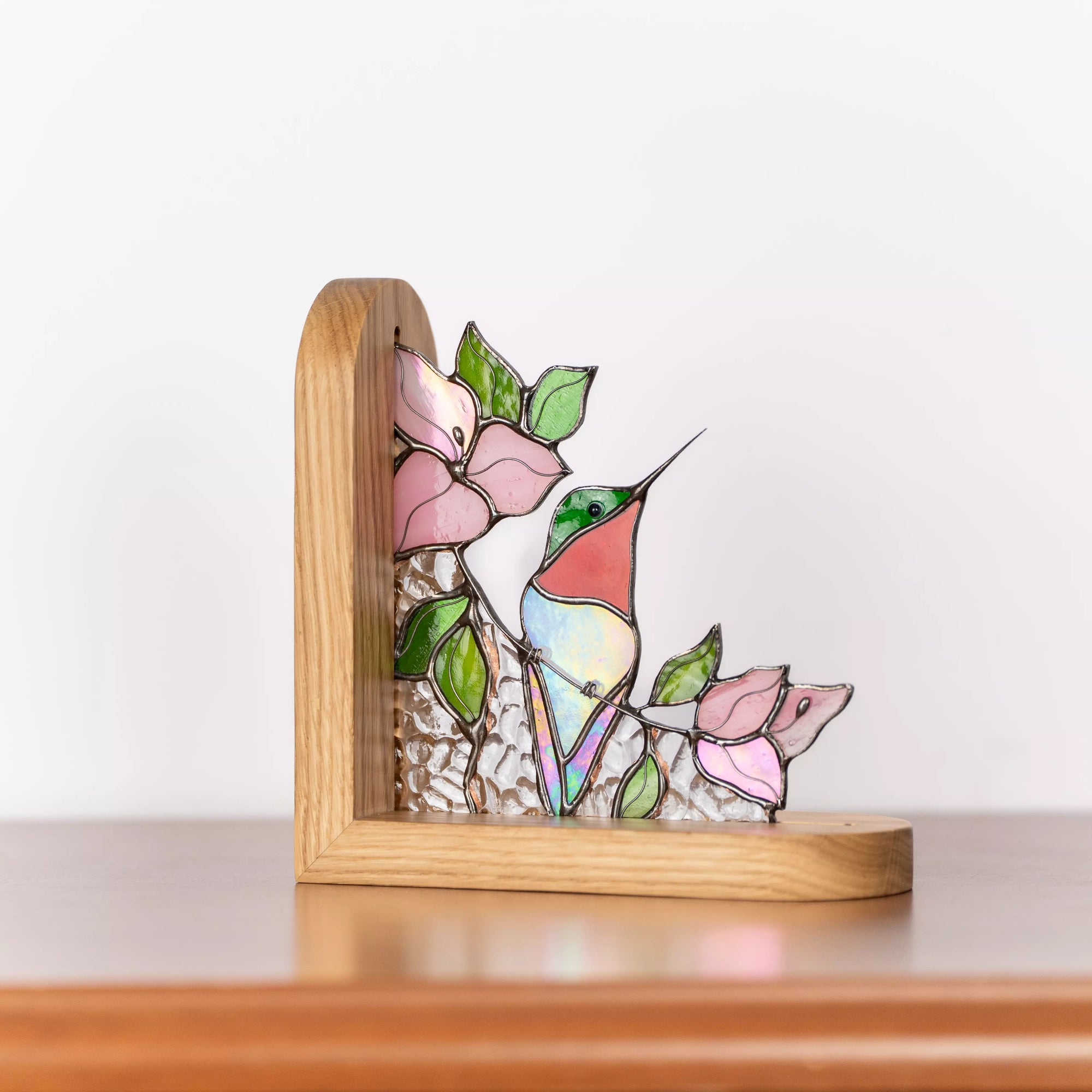 Handmade stained glass hummingbird bookend with iridescent glass, flowers, and a solid wooden stand.