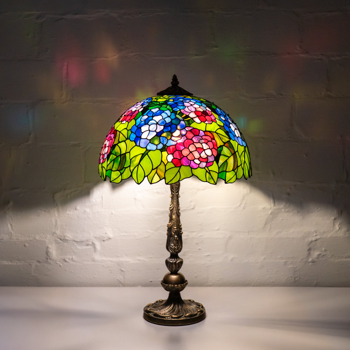 Stained glass lamp lights up a dark room with vivid flower patterns on the wall.