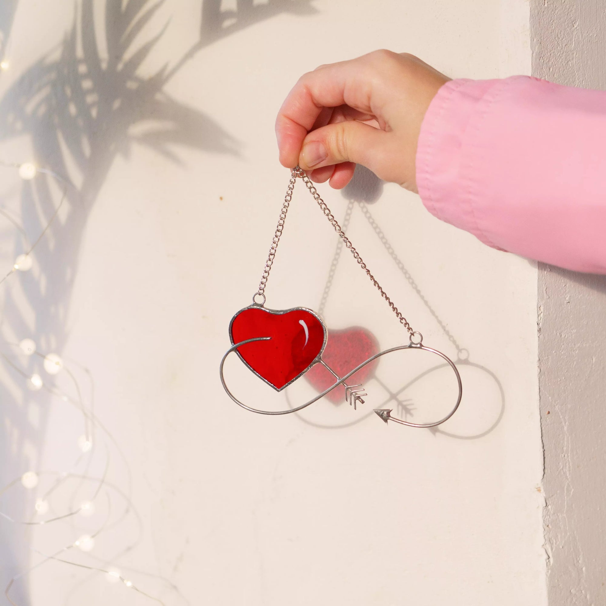 Infinity love stained glass suncatcher catching sunlight on a window.