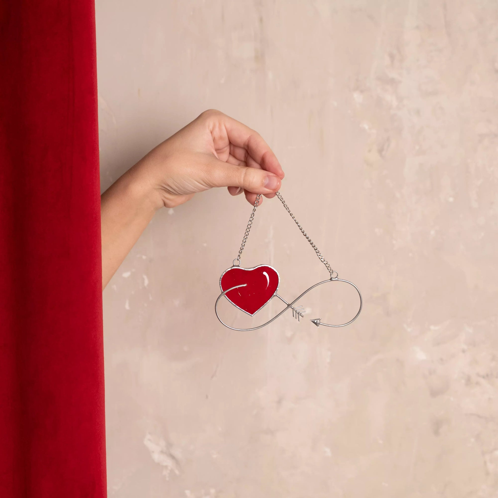 Infinity love stained glass suncatcher held in hand to show size and detail.