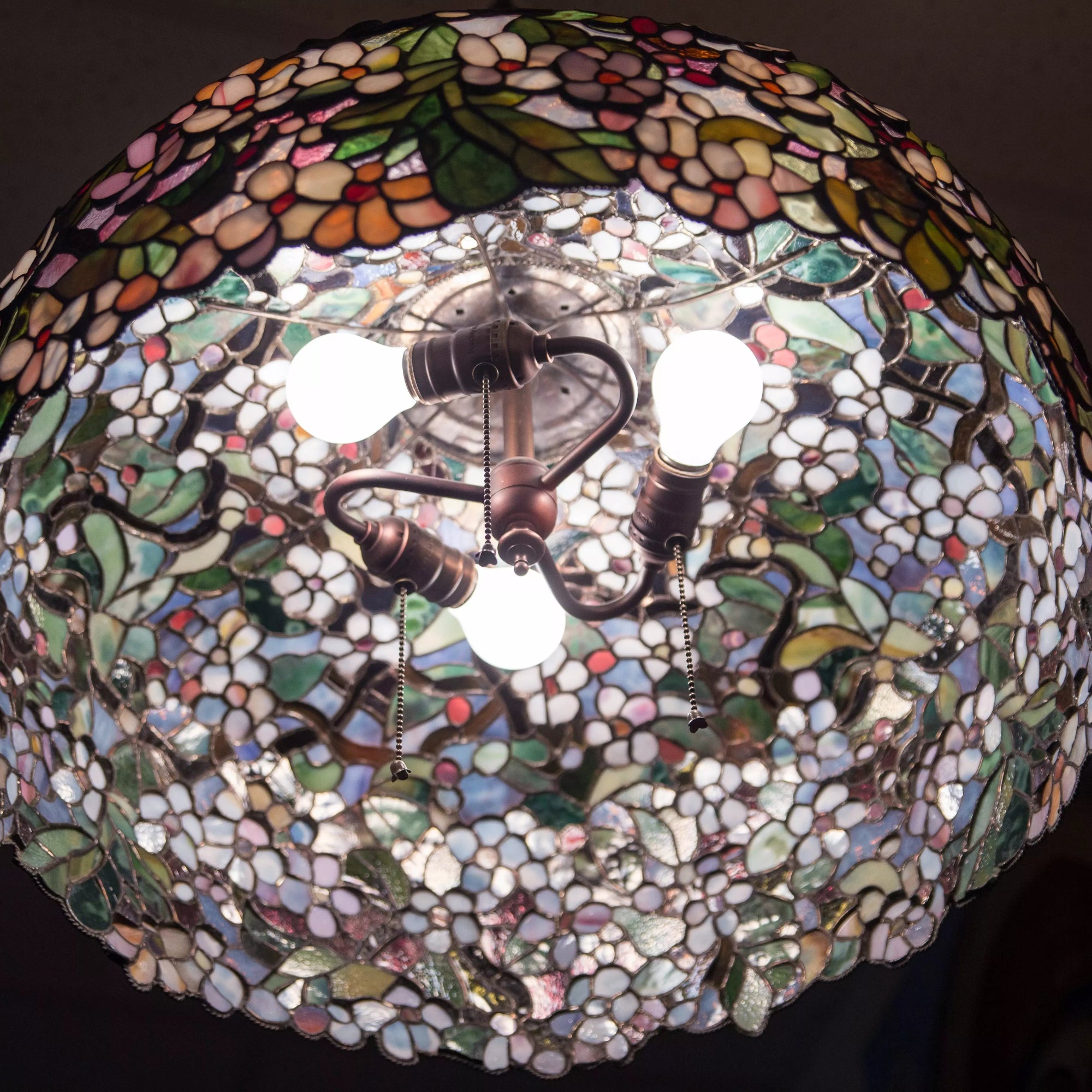 Interior perspective showing bulbs mounted inside stained glass floral chandelier shade.