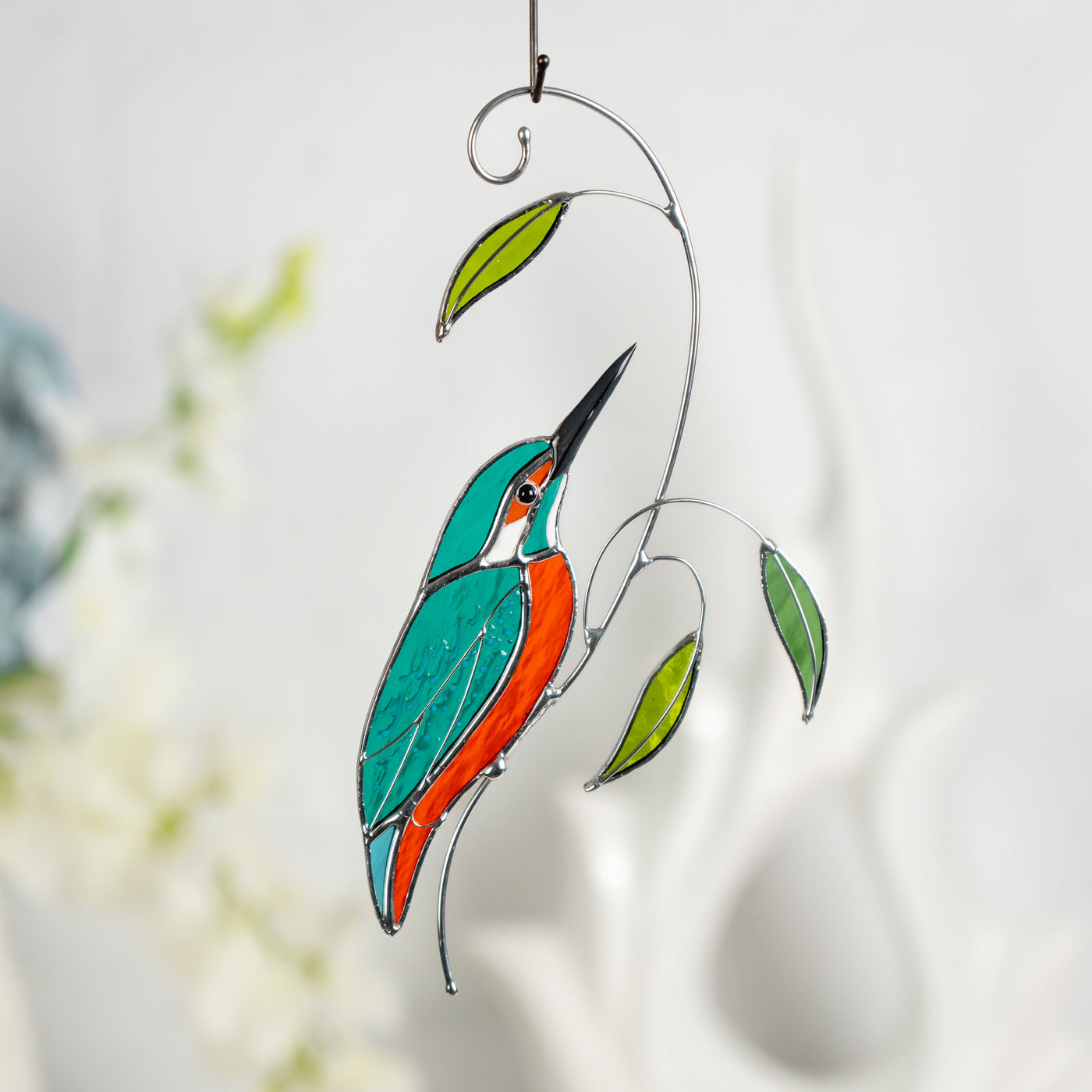 Stained glass kingfisher bird with graceful curves and bright green glass leaves.