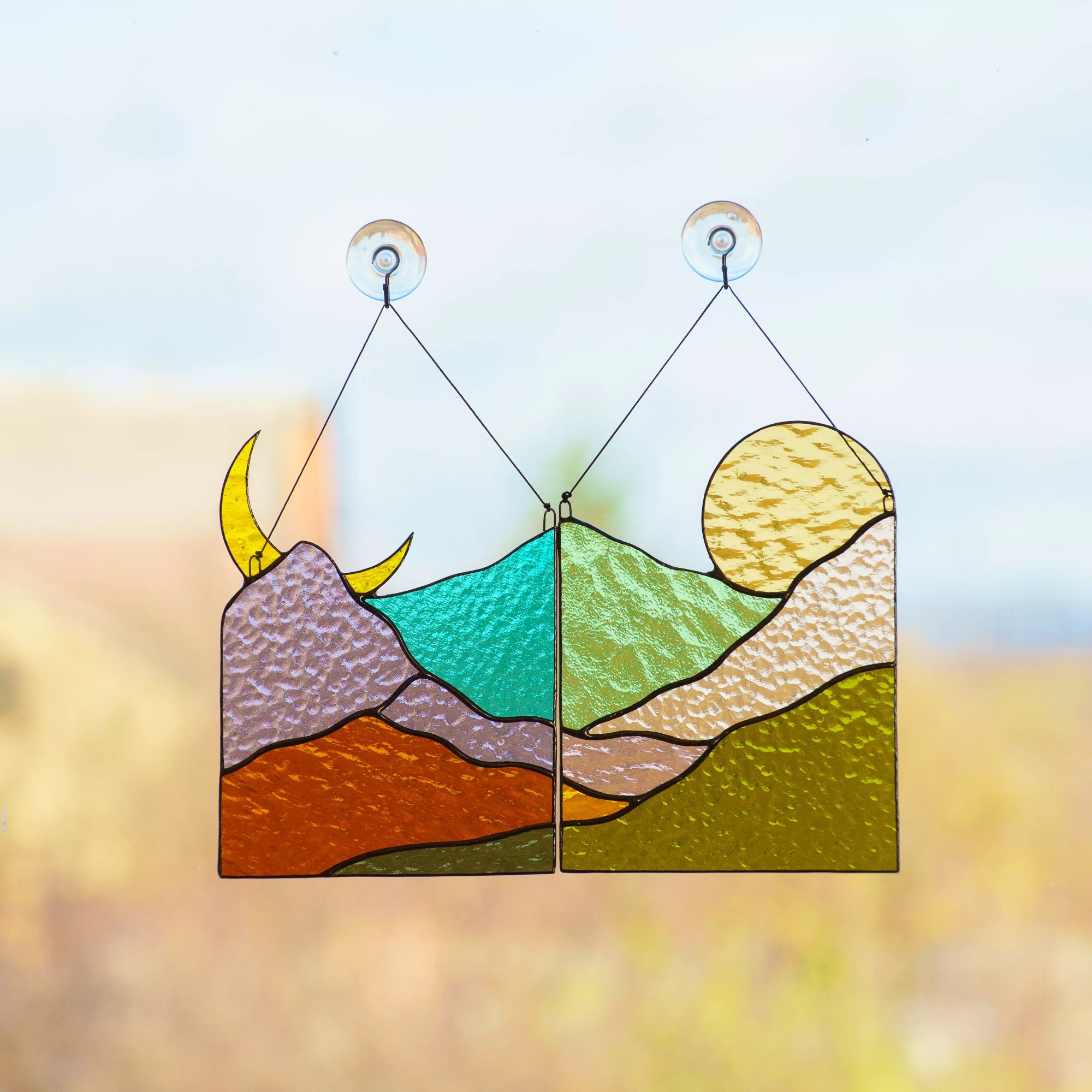 Two matching stained glass suncatchers depicting a moonlit mountain night and a sunlit mountain day.