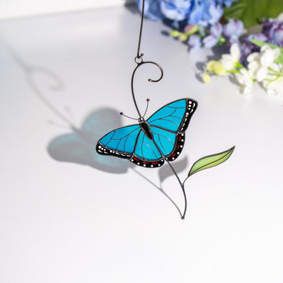 Glass morpho butterfly decor with blue shadow cast on a white surface.