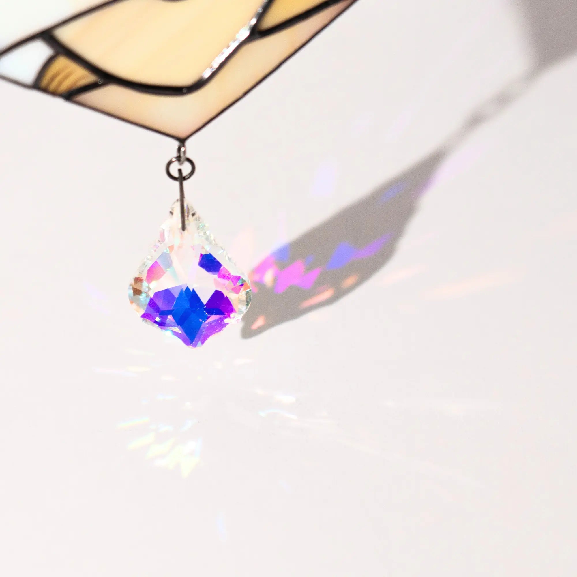 Multicolored crystal pendant casting a light shadow on a white background